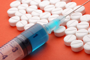 pills and syringe on an orange background